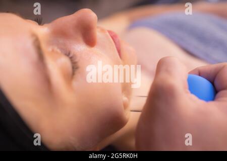 Femme reçoit de rajeunissement du visage massage du visage saigner à l'acupuncture wellness spa Banque D'Images