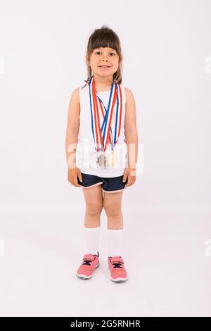 Petite fille aux cheveux foncés avec des médailles de champion de sport. Sport et victoire Banque D'Images