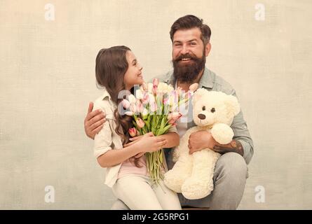 Je souhaite à Heureux anniversaire. Joyeux anniversaire en famille. Le père et la fille tiennent des tulipes et des jouets. Fête des pères. Fête des femmes. Anniversaire Banque D'Images