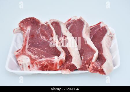 tranches d'agneau fraîchement hachées décorées dans un plat sur fond blanc, portion de longe Banque D'Images