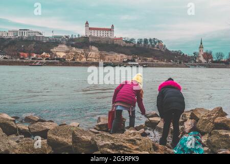 Deux enfants jouant au bord du Danube avec vue sur le château de Bratislava, Slovaquie, Europe Banque D'Images