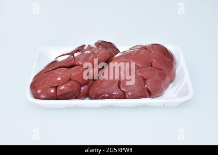 rein d'agneau frais isolé dans un plat sur fond blanc, viande crue gros plan, morceau de mouton Banque D'Images