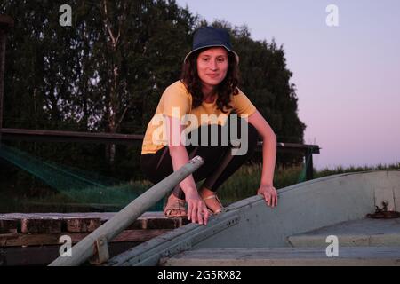 La fille tire le bateau debout sur l'eau de la jetée en bois avec sa main. Banque D'Images