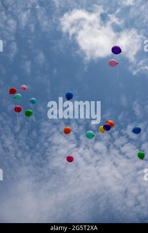 des ballons de gel colorés et multicolores volent dans un groupe de ciel bleu vif Banque D'Images