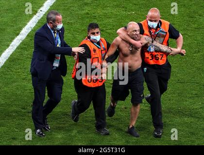 Un envahisseur de terrain est enlevé par la sécurité lors du match de l'UEFA Euro 2020 Round de 16 à Hampden Park, Glasgow. Date de la photo: Mardi 29 juin 2021. Banque D'Images