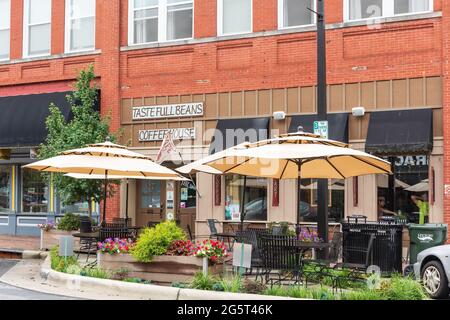 HICKORY, NC, USA-22 JUIN 2021: Vue diagonale avant de Taste Full Beans Coffeehouse, avec des fleurs colorées et de la verdure entourant les tables de trottoir. Banque D'Images