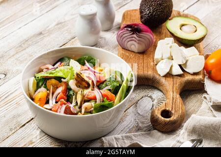 Salade méditerranéenne d'été délicieuse et saine. Moules, crevettes, saumon, tomates, salade de glace, avocat, oignon rouge, épices et huile d'olive. STI gastronomique Banque D'Images