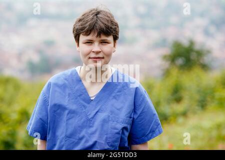 25 juin 2021, Rhénanie-Palatinat, Neustadt an der Weinstraße: Clara Mansmann, bénévole fédérale chez BG Klinik Ludwigshafen, se tient dans un vignoble portant des vêtements chirurgicaux chez elle. Depuis le 1er juillet 2011, le Service fédéral des bénévoles offre des possibilités d'orientation professionnelle à des personnes engagées. Photo: Uwe Anspach/dpa Banque D'Images