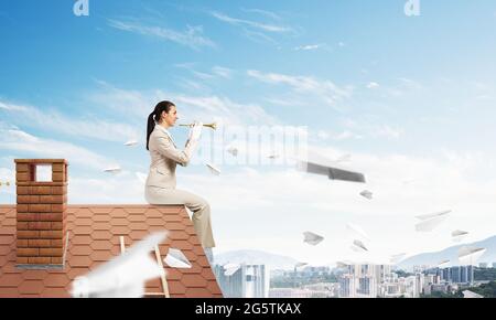 Attractive young woman playing trumpet sur toit Banque D'Images