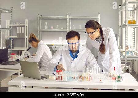 Groupe de jeunes scientifiques travaillant dans un laboratoire pharmaceutique ou biotechnologique moderne Banque D'Images