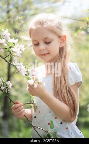 Petite fille adorable parmi l'arbre en fleur dans le jardin de pomme Banque D'Images