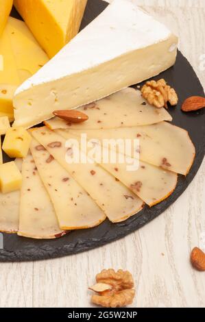 Différents types de fromage sur un tableau noir de graphite avec des abricots séchés, des noix. Vue de dessus Banque D'Images