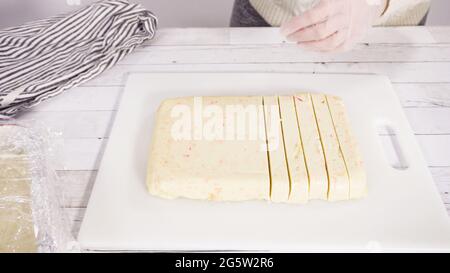 Étape par étape. Coupe de fudge de canne à sucre fait maison sur un tableau de découpe blanc. Banque D'Images