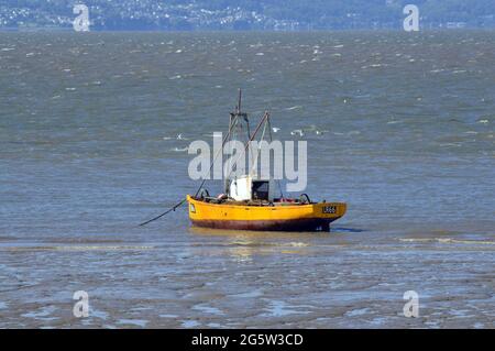 MORECAMBE. LANCASHIRE. ANGLETERRE. 06-12-21. Un bateau à coque jaune qui monte sur la marée entrante dans la baie de Morecambe. Dans la distance est la côte de Cumbrian . Banque D'Images