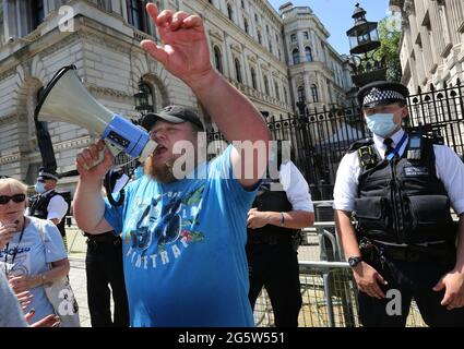 Un manifestant se tient devant la police et scanne des slogans pendant la manifestation à Westminster.les manifestants se rassemblent devant Downing Street pour protester contre l'annonce par Boris Johnson d'une extension des réglementations de confinement au Royaume-Uni qui, selon eux, portent atteinte à leurs droits humains, protestent également contre le port continu de masques et être soumis au programme de vaccination. Banque D'Images