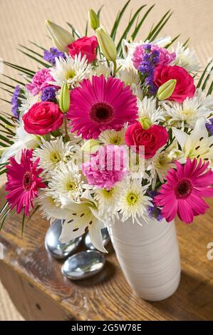 Un vase spectaculaire de fleurs roses et blanches sur une table basse dans un cadre de chambre Banque D'Images