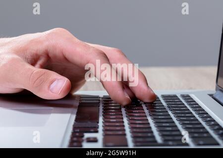 Gros plan de l'homme d'affaires caucasien tapant sur le clavier, isolé sur fond gris Banque D'Images