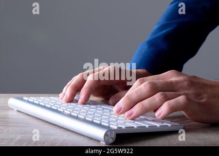 Gros plan de l'homme d'affaires caucasien tapant sur le clavier, isolé sur fond gris Banque D'Images