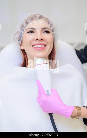 La poignée de l'appareil de radiofréquence sur le menton d'une femme visage lors d'une procédure de rajeunissement de la peau beauté. Esthéticienne fait un matériel Banque D'Images