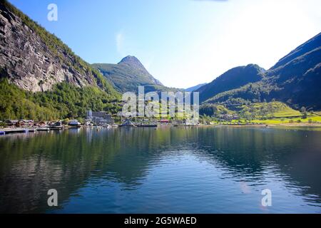 Belle vue sur la ville de Geiranger depuis l'eau, un jour d'été. Réflexions des montagnes dans le fjord. Geiranger, Norvège. Banque D'Images