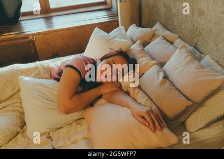 Une jeune femme dormant paisiblement dans sa chambre, se détendant. Femme calme et paisible dormant au lit. Banque D'Images