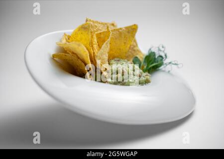 gros plan de la sauce guacamole dans un bol avec avocat et nachos sur fond blanc Banque D'Images