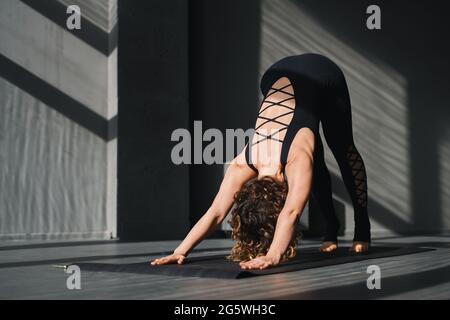 Une jeune femme pratiquant le yoga pose dans un fond urbain par temps ensoleillé Banque D'Images