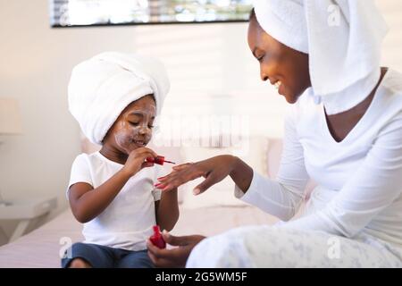 Bonne mère africaine américaine et fille se détendant dans la chambre, fille peignant les ongles de la mère Banque D'Images