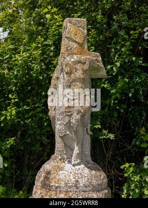 Une statue fortement endommagée de deux figures, un Christ sur la croix sur une colonne de pierre près du bord de la route près de Bruisyard Hall, Suffolk, Royaume-Uni Banque D'Images