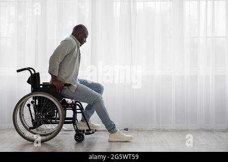 Concentré tendu mature africain américain homme handicapé se tient debout de fauteuil roulant Banque D'Images