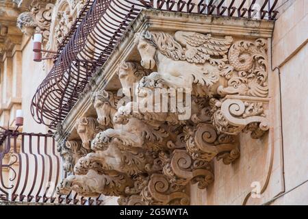 Noto, Syracuse, Sicile, Italie. Des figures de pierre finement sculptées soutenant un balcon ornemental sur la façade baroque du Palazzo Nicolaci di Villadorata. Banque D'Images