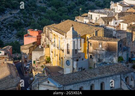 Ragusa, Sicile, Italie. Vue sur les toits pittoresques de Ragusa Ibla, coucher de soleil, maisons accrochée à la colline abrupte au-dessus de gorges boisées. Banque D'Images