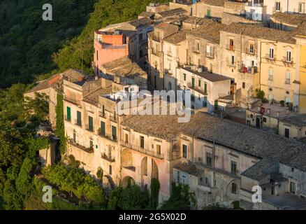 Ragusa, Sicile, Italie. Vue sur les toits pittoresques de Ragusa Ibla, coucher de soleil, maisons accrochée à la colline abrupte au-dessus de gorges boisées. Banque D'Images