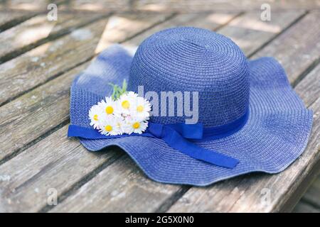 chapeau bleu allongé sur un banc en bois avec un petit bouquet de pâquerettes. bouquet de fleurs sauvages et de prairie. Une photo romantique d'un été mignon. Vacances Banque D'Images