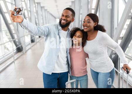 Famille noire voyageant, emportant le selfie sur le téléphone portable à l'aéroport Banque D'Images