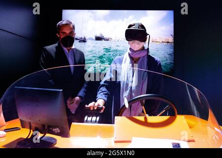 Un visiteur du congrès qui contrôle à distance un drone marin tout en étant supervisé par un agent Orange sur le stand Orange du Mobile World Congress, au cours du troisième jour de l'événement. Grâce à 5G, un bateau sans pilote situé dans le port de ValenciaÕs pouvait être contrôlé, avec presque aucune latence, depuis Barcelone, à environ 300km. Bien que le contrôle des drones et des véhicules à distance ne soit pas quelque chose de nouveau, le faire dans un environnement maritime présente un défi difficile en raison des interférences de la mer avec les ondes radio, et n'a pas été vu auparavant. L'utilisation d'un casque de réalité virtuelle et d'une carte sim de navigation Banque D'Images