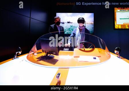 Un visiteur du congrès qui contrôle à distance un drone marin tout en étant supervisé par un agent Orange sur le stand Orange du Mobile World Congress, au cours du troisième jour de l'événement. Grâce à 5G, un bateau sans pilote situé dans le port de ValenciaÕs pouvait être contrôlé, avec presque aucune latence, depuis Barcelone, à environ 300km. Bien que le contrôle des drones et des véhicules à distance ne soit pas quelque chose de nouveau, le faire dans un environnement maritime présente un défi difficile en raison des interférences de la mer avec les ondes radio, et n'a pas été vu auparavant. L'utilisation d'un casque de réalité virtuelle et d'une carte sim de navigation Banque D'Images