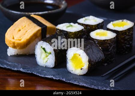 Sushi maki végétarien fait maison sur plaque d'ardoise avec baguettes et bol de sauce soja à l'arrière Banque D'Images