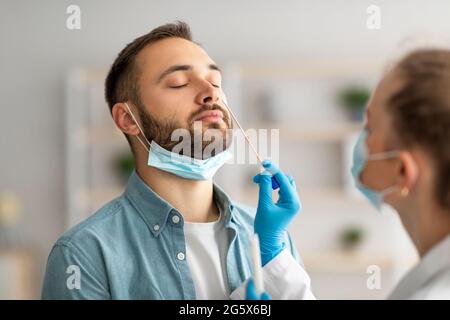 Test PCR du coronavirus nasal. Médecin utilisant un écouvillon pour prélever un échantillon de virus covid chez un jeune type potentiellement infecté Banque D'Images