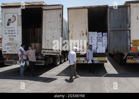 Bab Al Hawa, Syrie. 30 juin 2021. Les Syriens inspectent des camions chargés d'aide humanitaire fournis par l'organisation du Programme alimentaire mondial après leur entrée de Turquie dans les territoires syriens du nord-ouest par le passage frontalier de Bab Al-Hawa, dont le mandat expire le 10 juillet 2021. Credit: Aras Alkharboutli/dpa/Alamy Live News Banque D'Images