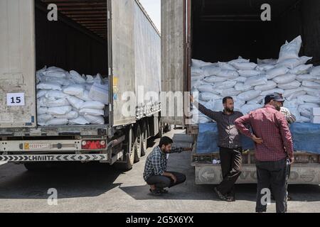 Bab Al Hawa, Syrie. 30 juin 2021. Les Syriens inspectent des camions chargés d'aide humanitaire fournis par l'organisation du Programme alimentaire mondial après leur entrée de Turquie dans les territoires syriens du nord-ouest par le passage frontalier de Bab Al-Hawa, dont le mandat expire le 10 juillet 2021. Credit: Aras Alkharboutli/dpa/Alamy Live News Banque D'Images