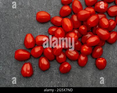 Plan de la vue des petites tomates prune sur un fond gris texturé Banque D'Images