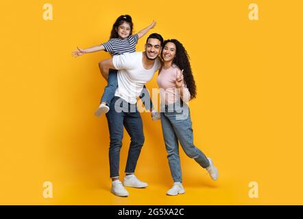 Joyeux Moyen-Orient famille de trois s'amuser ensemble sur fond jaune Banque D'Images