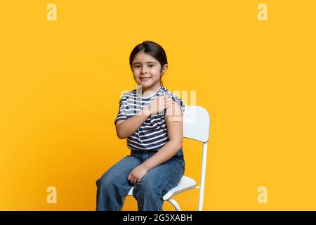 Portrait de la petite fille arabe mignonne montrant le bras après la vaccination du coronavirus Banque D'Images