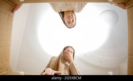 Deux filles se sentent dégoûtées après avoir ouvert la boîte en carton et de trouver quelque chose de misérable ou de stinky. Banque D'Images