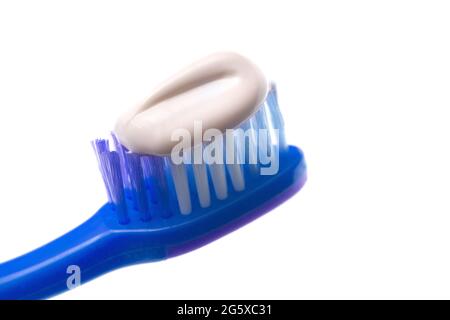 Une brosse à dents simples sur un fond blanc avec du dentifrice appliqué sur les soies Banque D'Images