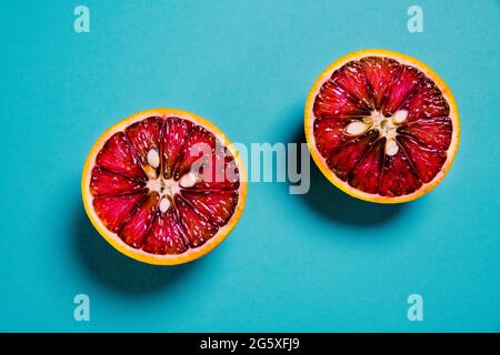 Deux tranches de sang orange sur fond bleu. Concept alimentaire. Minimale. Banque D'Images