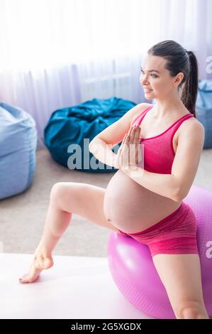 Belle femme enceinte faisant des exercices sur une balle de fitness. Femme enceinte au cours du dernier trimestre faisant du yoga. Banque D'Images