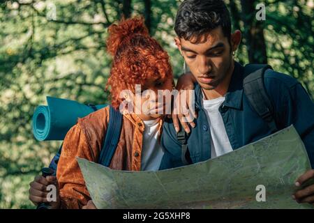jeune couple multiethnique lors d'un voyage en sac à dos en regardant la carte Banque D'Images