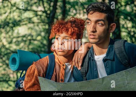 jeune couple multiethnique lors d'un voyage en sac à dos en regardant la carte Banque D'Images